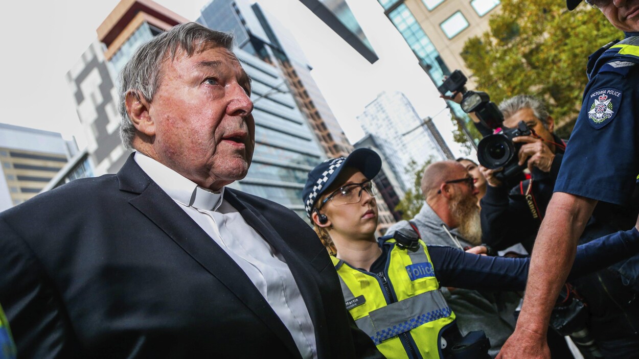 Le cardinal arrive en tenue, le teint rouge et les yeux inquiets. Il est entouré de policier et un photographe est visible au second plan. Le cardinal arrive en tenue, le teint rouge et les yeux inquiets. Il est entouré de policier et un photographe est visible au second plan.