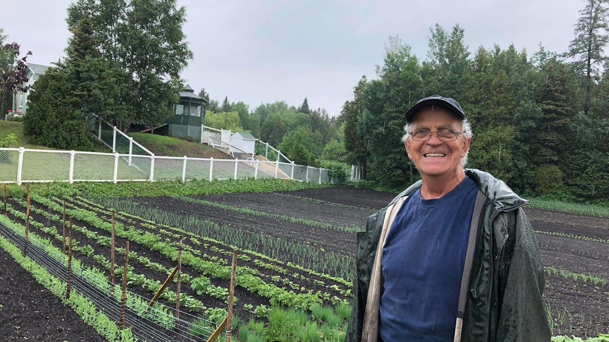 Ghislain Lebel est devant son potager et sourit à la caméra.