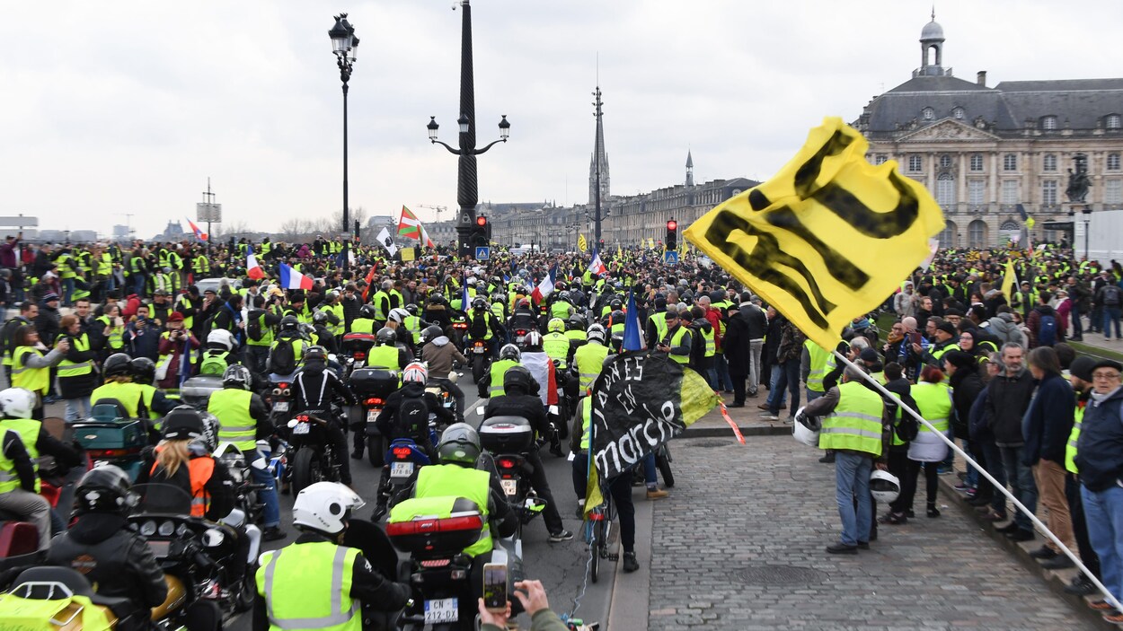 Des motocyclistes et des manifestants à pied sont réunis.