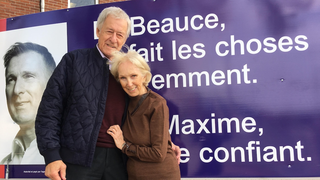 Gilles Bernier et Doris Rodrigue-Bernier posent devant une affiche électorale de Maxime Bernier.