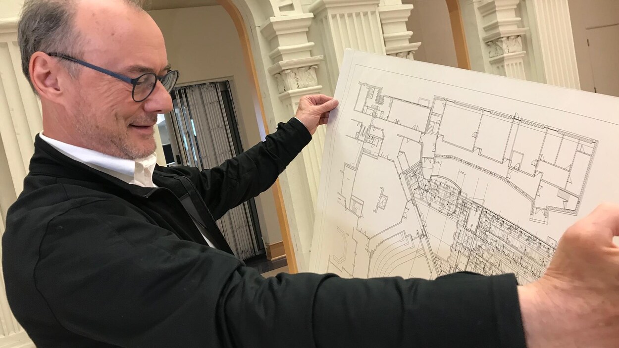 Le directeur du Centre du patrimoine tenant les plans de construction du centre.