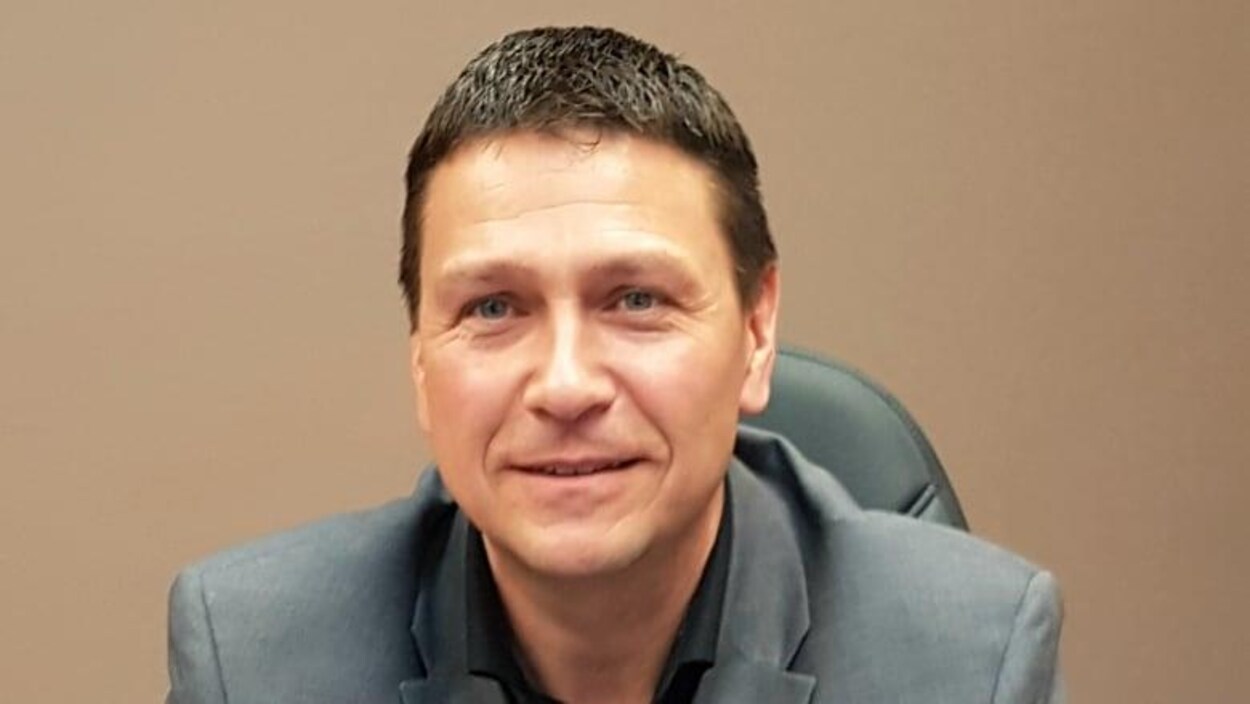 Gino Mallais assis sourit à la caméra.