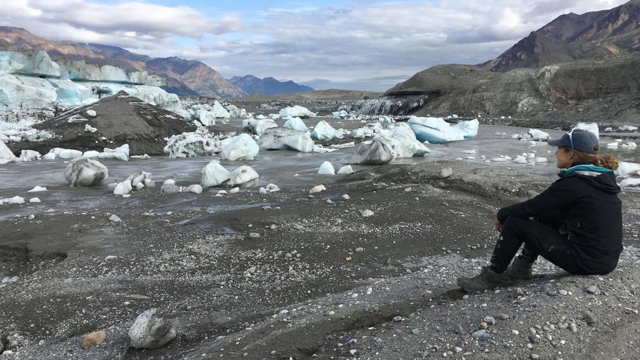 Une habitante de Whitehorse, Haley Digel, assise par terre observe le 15 juillet un grand espace se trouvait un lac du glacier Donjek.