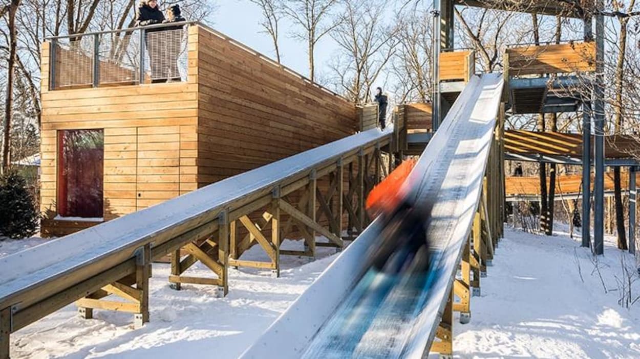 Une structure comprenant deux glissoires pour des toboggans installée dans un parc en hiver.