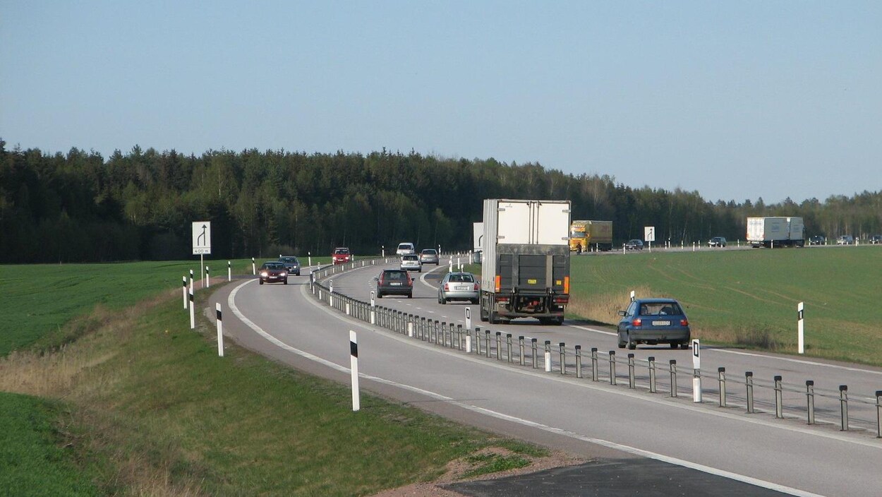 La clôture en métal reliée par des câbles sépare des voies rapides.