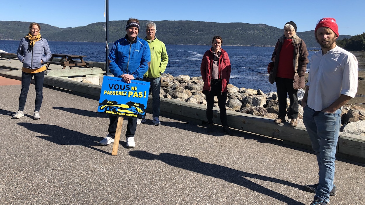 Six personnes posent devant le fjord. L'une d'elles tient une pancarte sur laquelle est écrit : «Vous ne passerez pas».