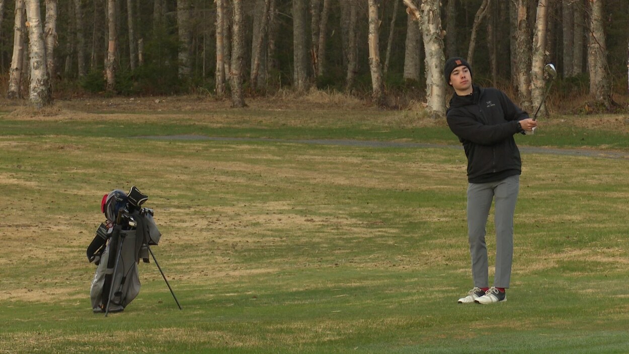 Un jeune garçon joue au golf.