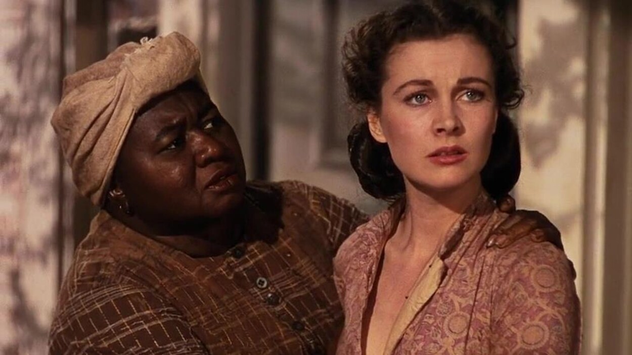 Une femme noire dans son personnage de servante de maison regarde une femme blanche le personnage de Scarlett