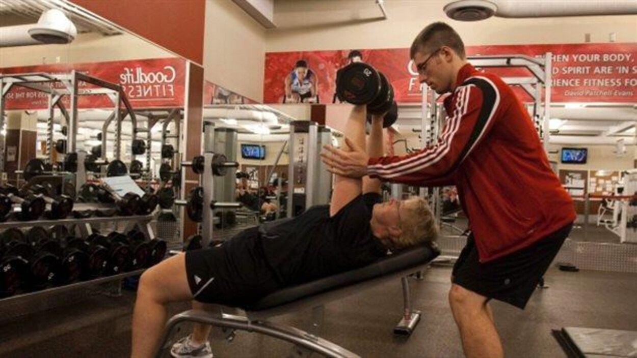 Un entraîneur de GoodLife Fitness aide une cliente Un entraîneur de GoodLife Fitness aide une cliente