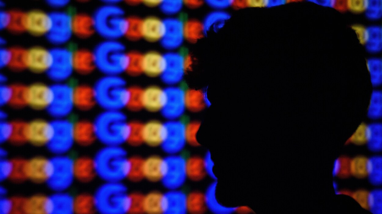 Un homme de profil se tient devant un mur où le mot Google est répété. Un homme de profil se tient devant un mur où le mot Google est répété.