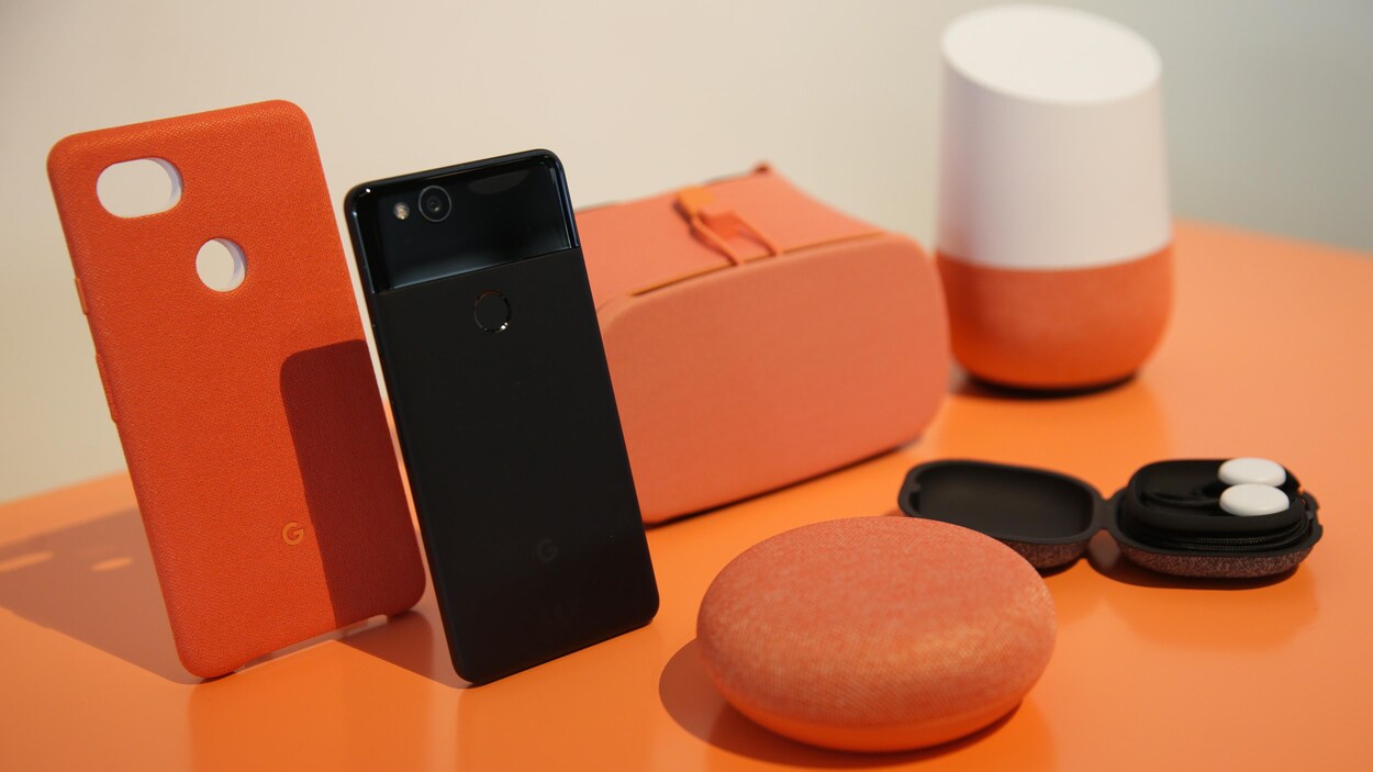Un téléphone, deux enceintes, une paire d'écouteurs et un casque de réalité virtuelle sont présentés sur un comptoir. Un téléphone, deux enceintes, une paire d'écouteurs et un casque de réalité virtuelle sont présentés sur un comptoir.