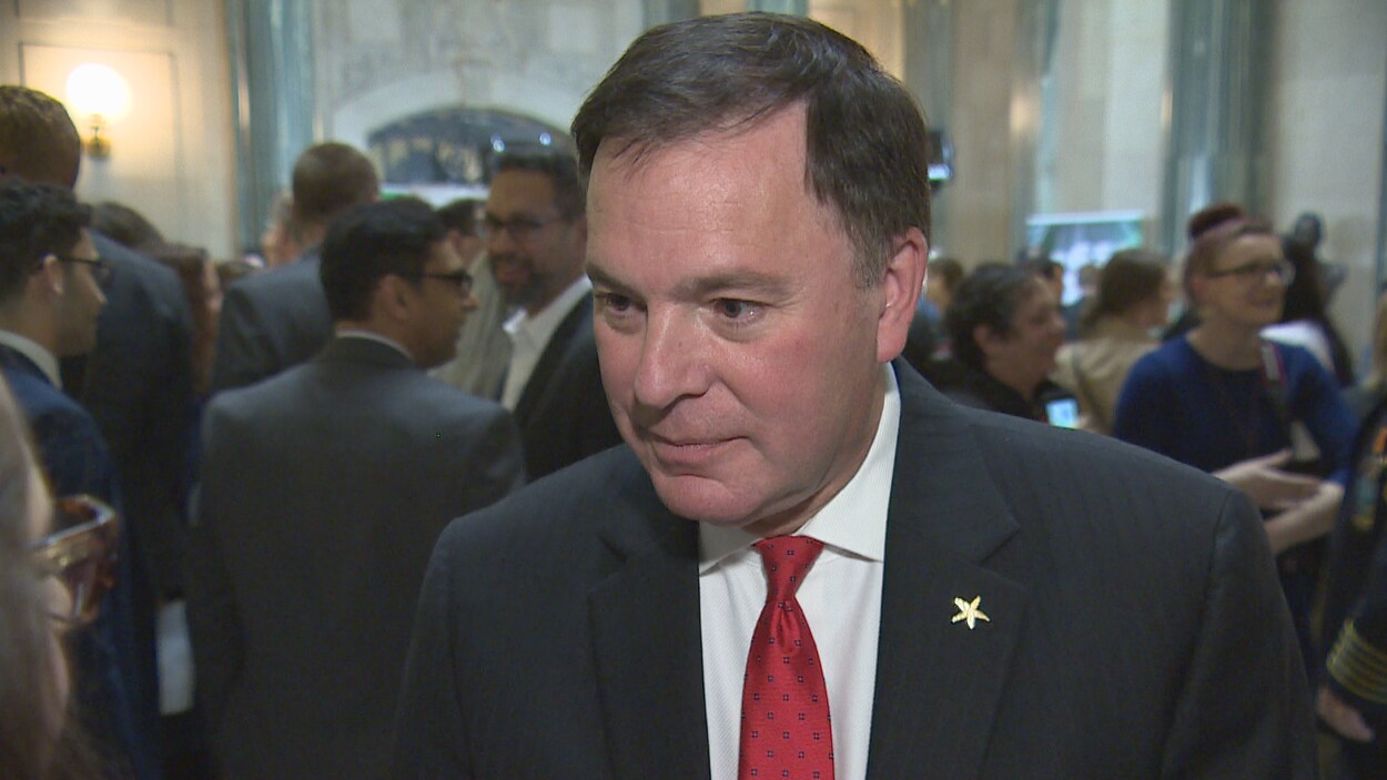 Gordon Wyant regarde les journalistes en écoutant leurs questions concernant le budget. Il porte une cravate rouge.