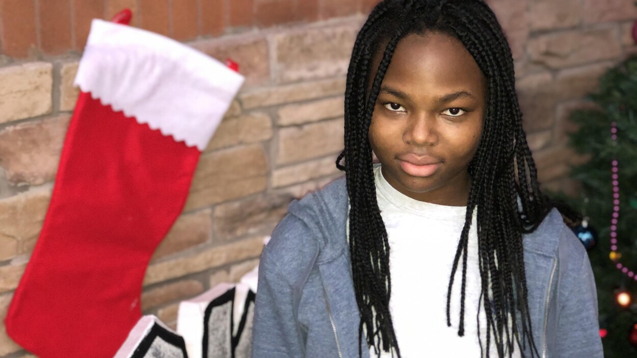 Grace Lingue devant un bas de noël et un mur de briques.