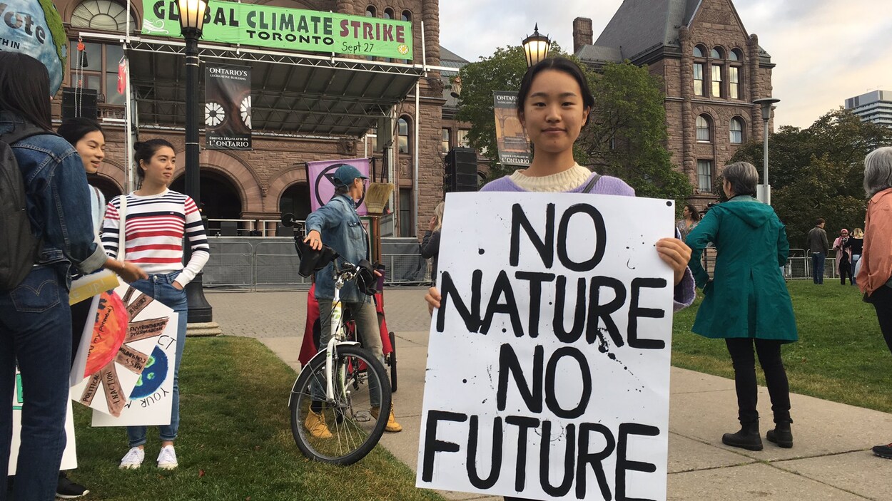 Grace Ma, 20 ans est devant Queen's Park et tient une pancarte sur laquelle est écrit : « No nature, no future »