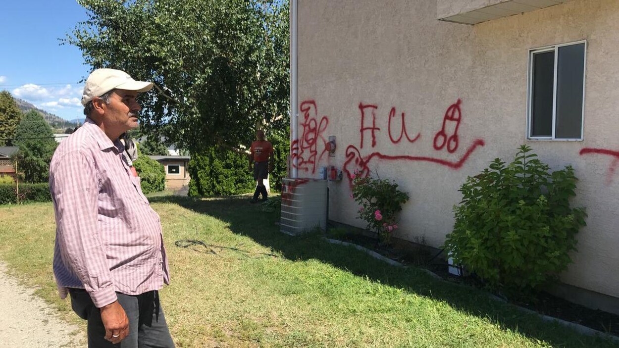 Un homme regarde les graffitis peints sur sa maison.
