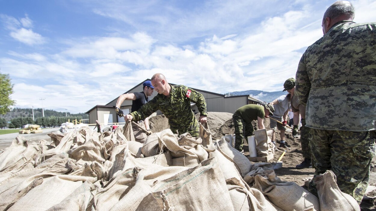 Des militaires remplissent des sacs de sable pour protéger la ville de Grand Forks en Colombie-Britannique, dont le centre-ville est inondé depuis une semaine. Des militaires remplissent des sacs de sable pour protéger la ville de Grand Forks en Colombie-Britannique, dont le centre-ville est inondé depuis une semaine.