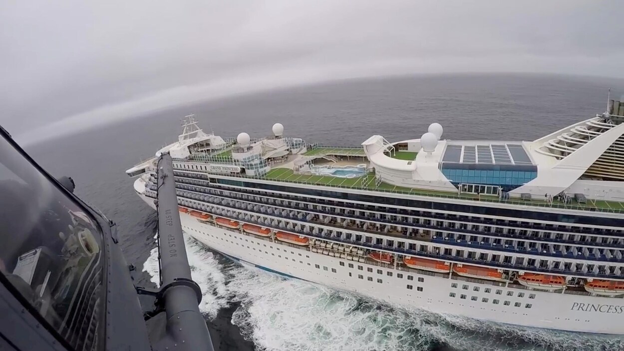 Vue aérienne du navire de croisière prise à partir d'un hélicoptère. Le pont supérieur du navire est désert.