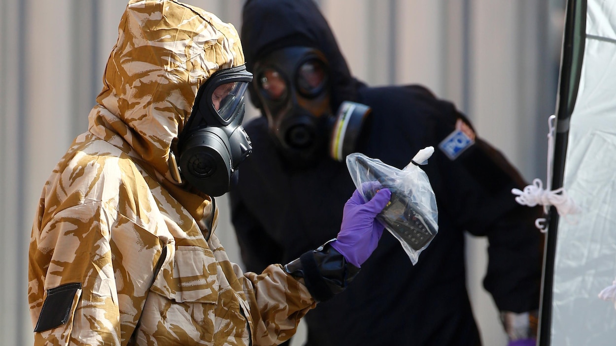Deux hommes en habit de protection, un d'entre eux tient un téléphone dans un sac de plastique. Deux hommes en habit de protection, un d'entre eux tient un téléphone dans un sac de plastique.