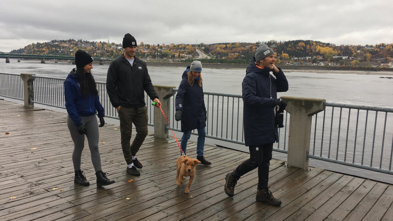 Deux hommes et deux femmes marchent en bordure du Saguenay. Un des deux hommes tient un chien en laisse.