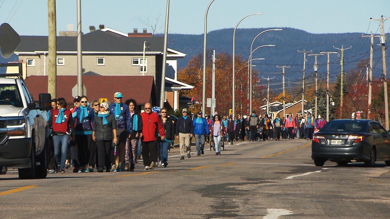 Un groupe de plusieurs dizaines de personnes marche dans la rue à Sept-Îles.
