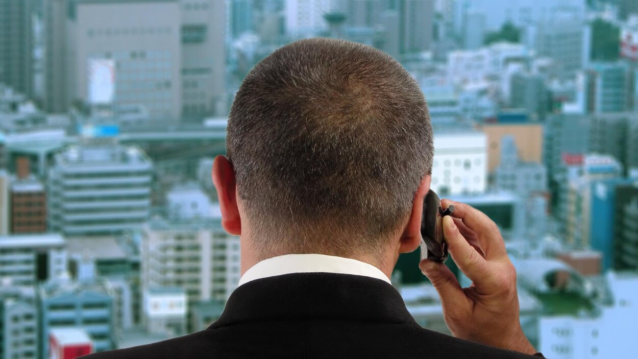 Un homme au téléphone regarde par la fenêtre d'un gratte-ciel.