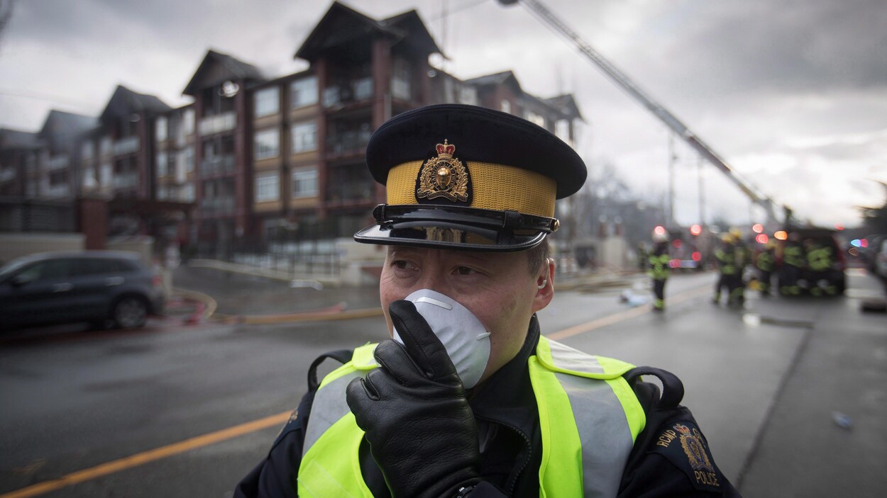 Un agent de la GRC tient un masque sur son visage.