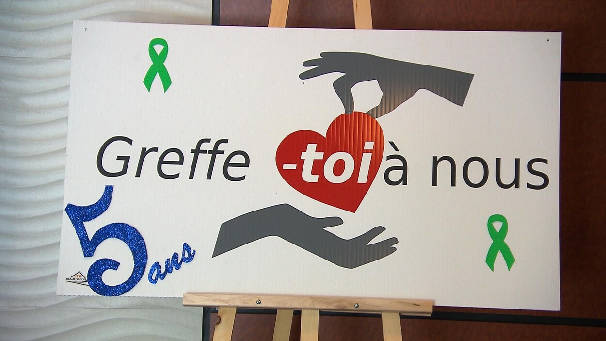 Le toi dans le logo de Greffe-toi à nous est dans un coeur rouge transmis d'une main à une autre.