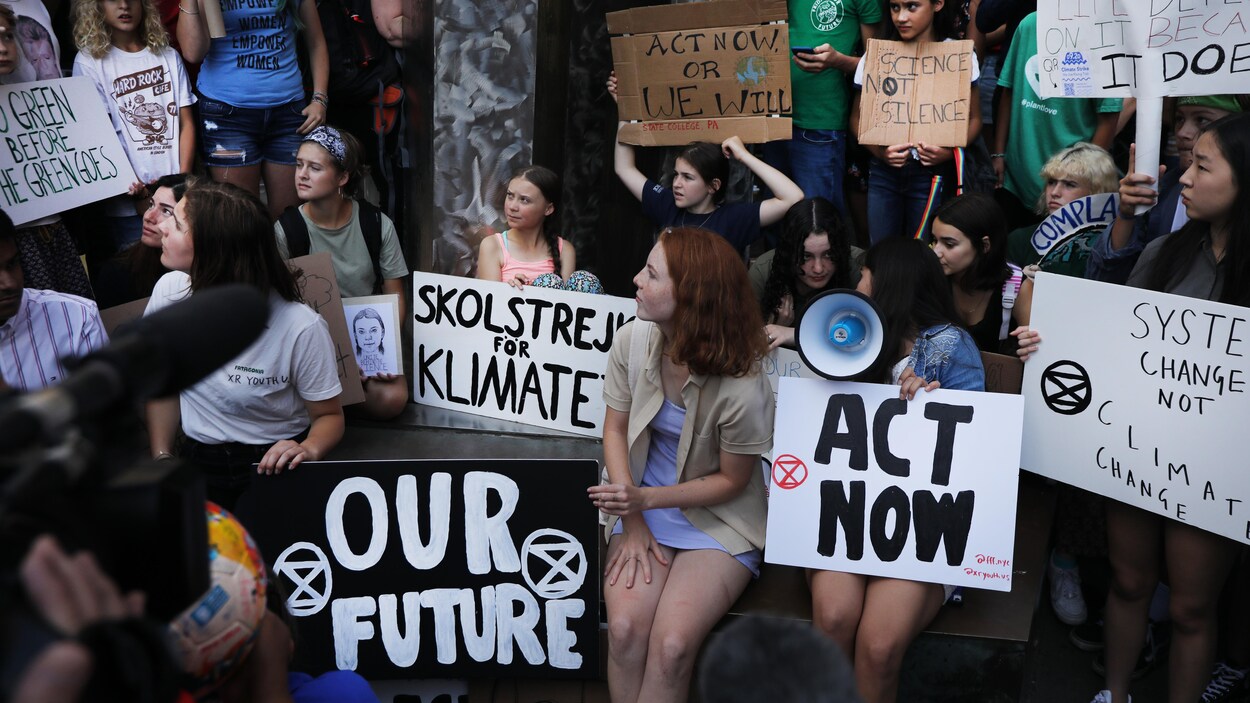 Des manifestants pour le climat sont assis avec des pancartes lors d'une manifestation à New York.