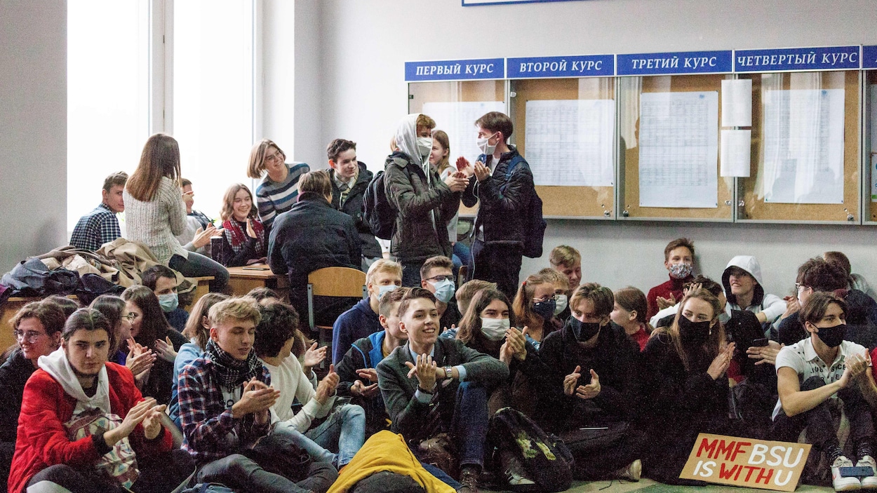 Des dizaines d'étudiants sont assis par terre ou autour de bureaux. Ils sont majoritairement souriants et tapent des mains.