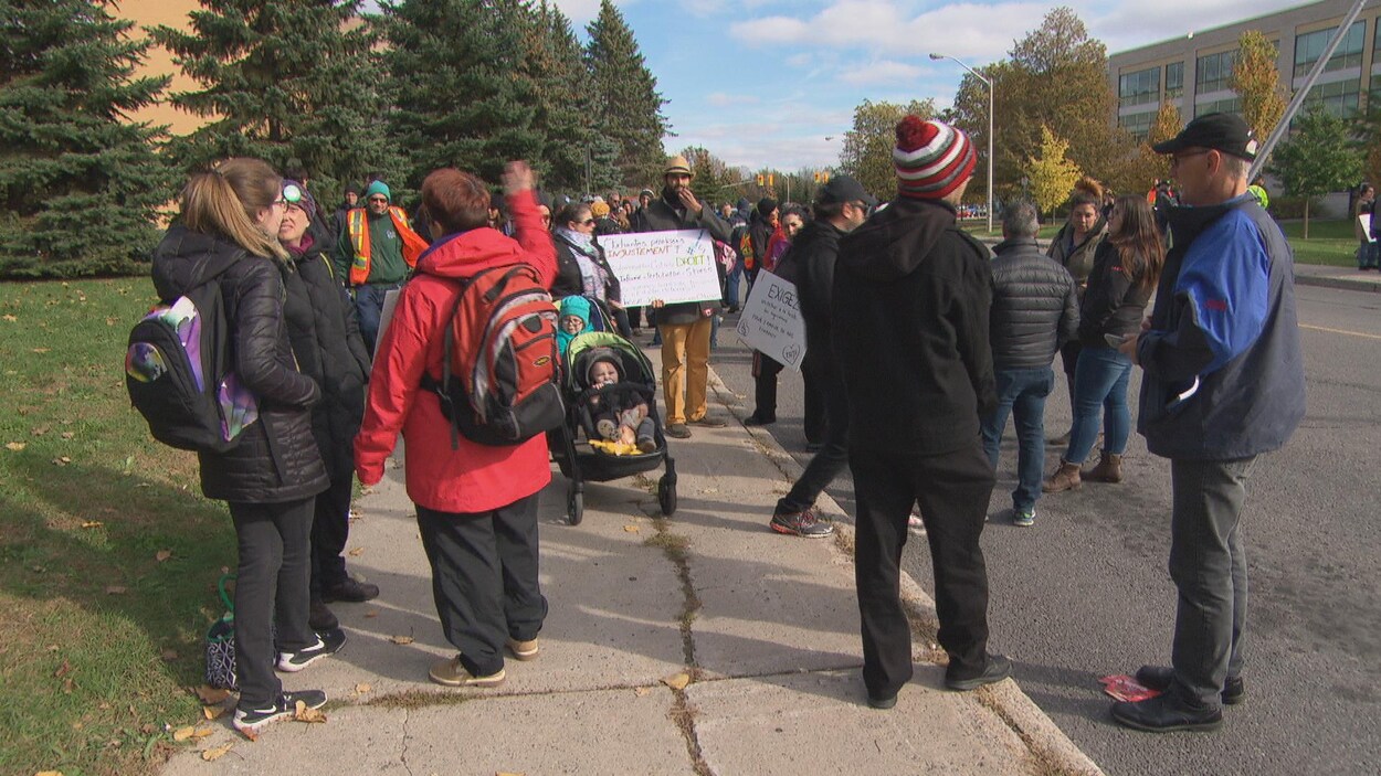 Des étudiants marchent avec des pancartes parmi les grévistes.