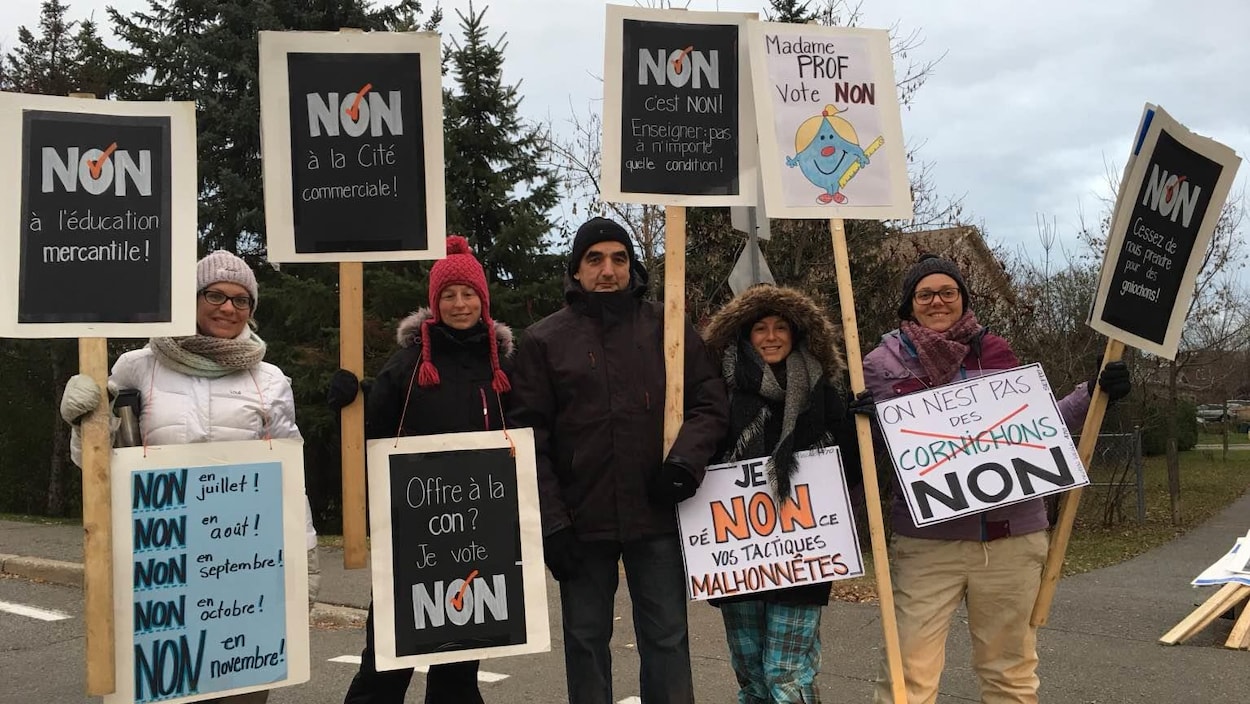 Les professeurs en grève arborent des pancartes indiquant qu'ils voteront contre l'offre patronale. Les professeurs en grève arborent des pancartes indiquant qu'ils voteront contre l'offre patronale.