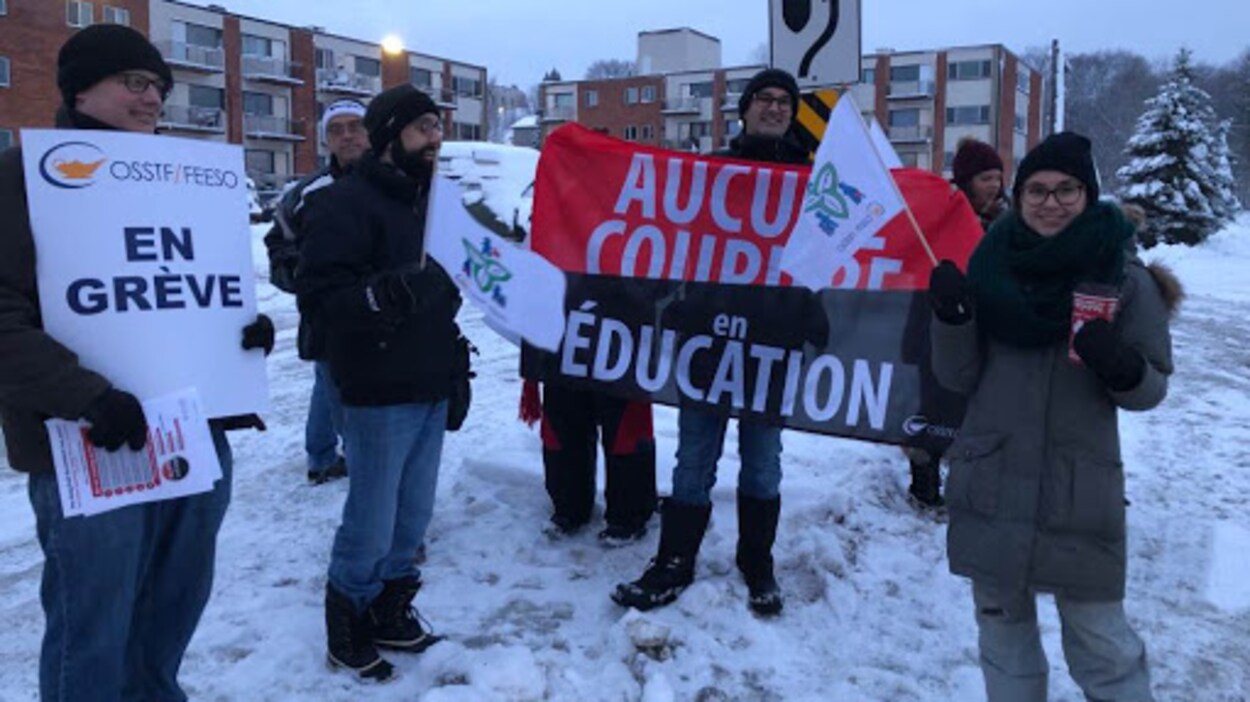 Des grévistes qui tiennent des pancartes et des bannières où il est écrit « En grève » et « Aucune coupure en éducation ».