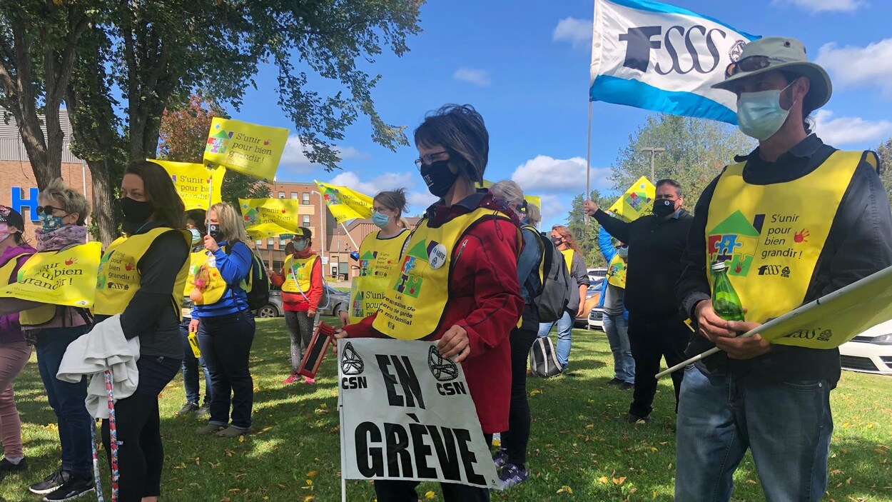 Une dizaine de personnes manifestent se tiennent debout sur la pelouse devant l'hôpital de Maria. Elles portent des couvre-visages et des dossards de leur syndicat.