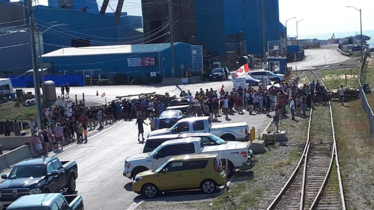 Des gens et des véhicules bloquent une entrée. Des gens et des véhicules bloquent une entrée.
