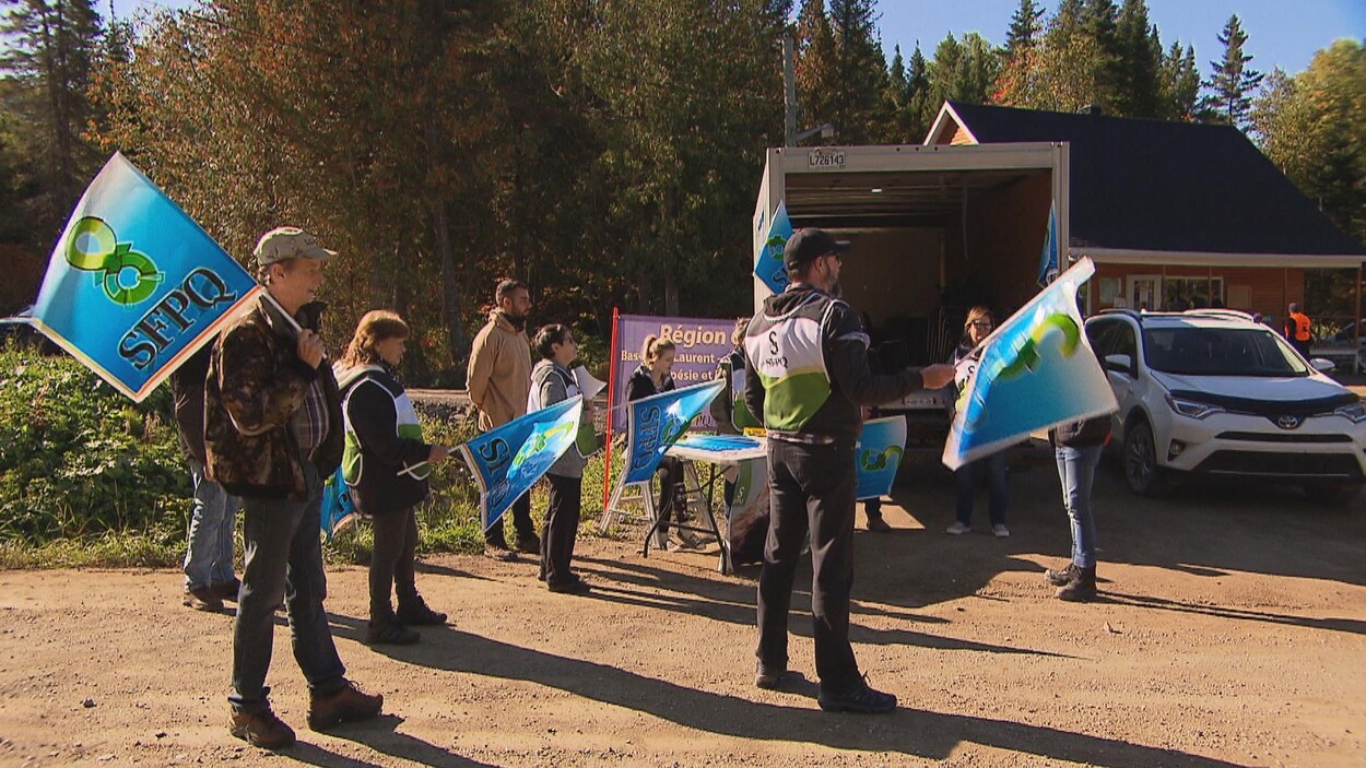 Des employés qui manifestent, drapeau syndical à la main.