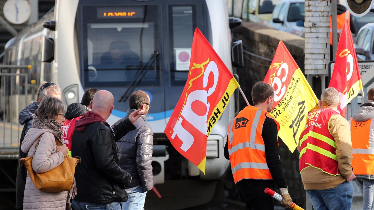 Des syndiqués passent devant un train.