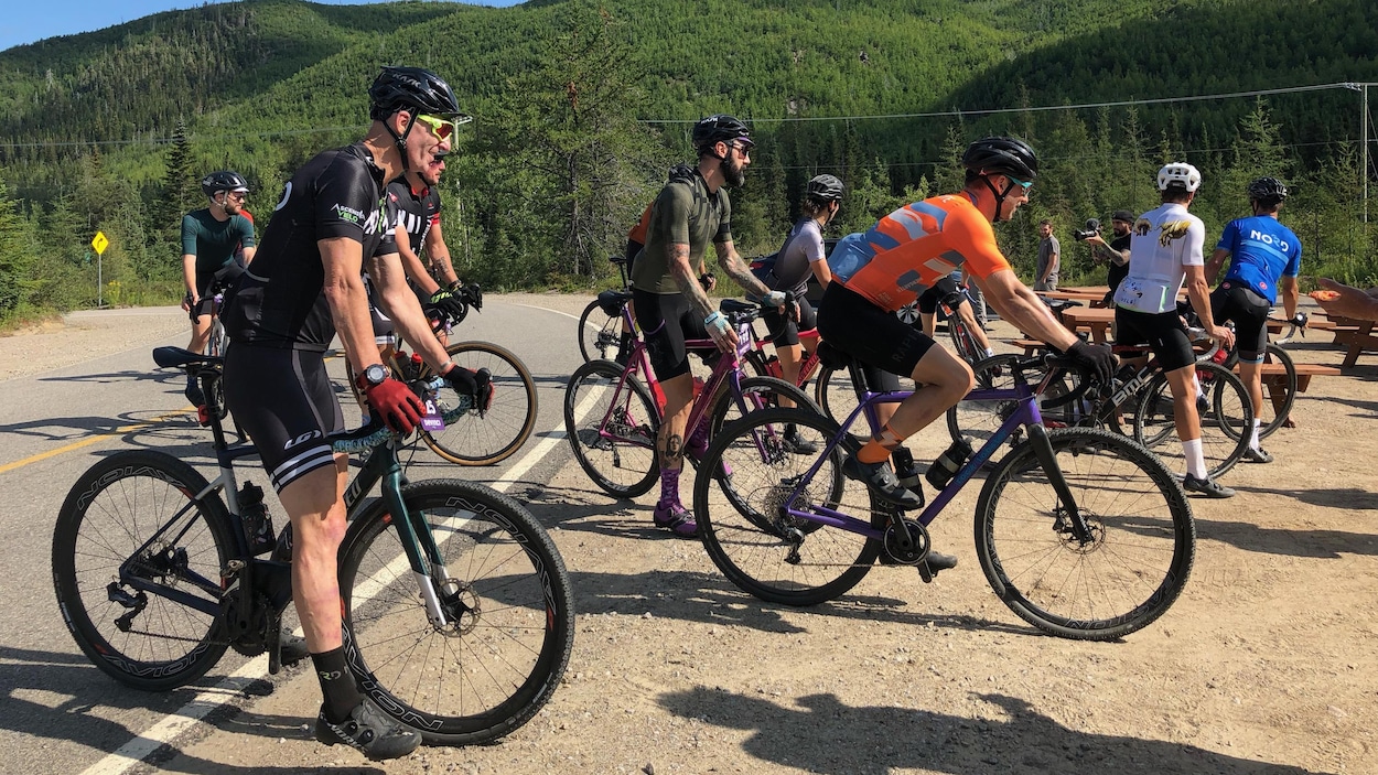 Des cyclistes quittent une route pour s'aventurer sur un chemin en gravier.