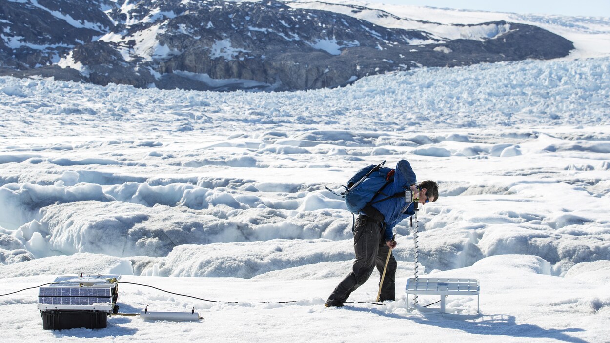 Un homme perce un trou dans un couvert de neige.