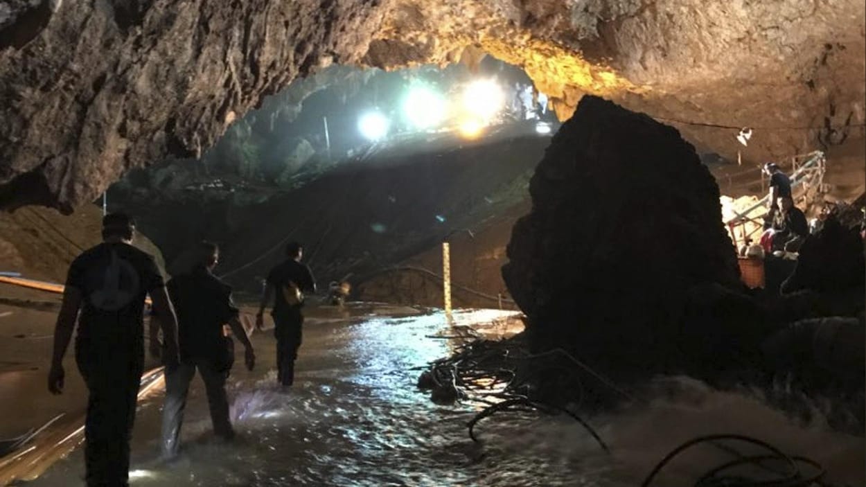 Trois secouristes marchent dans l'eau en file indienne.