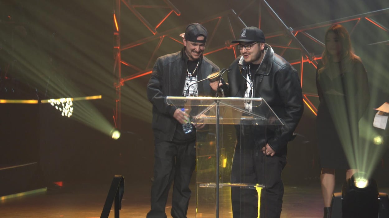 Les deux frères au podium recevant un prix à la salle J.-Antonio-Thompson.