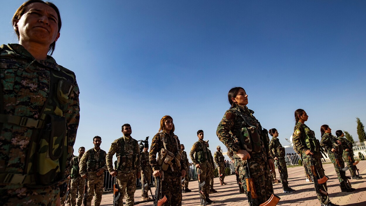 Des combattants kurdes en rangs ouverts, l'arme au pied.