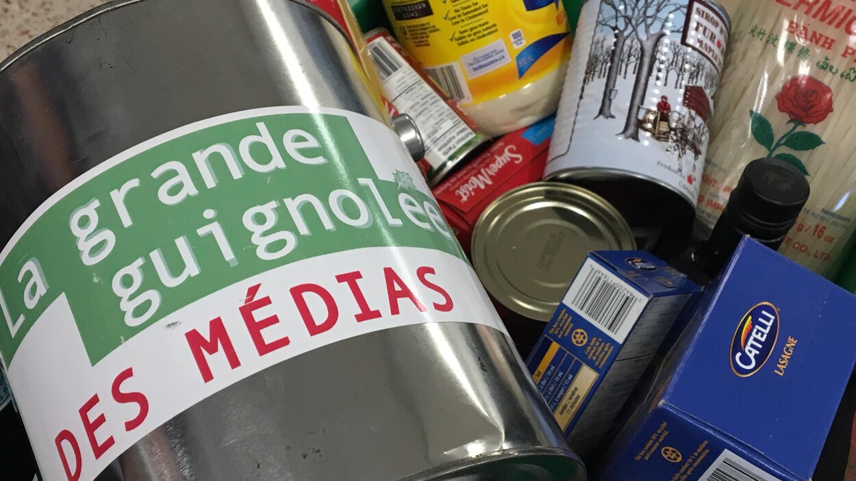 Une boîte de dons identifiée à la guignolée à côté de denrées non périssables Une boîte de dons identifiée à la guignolée à côté de denrées non périssables