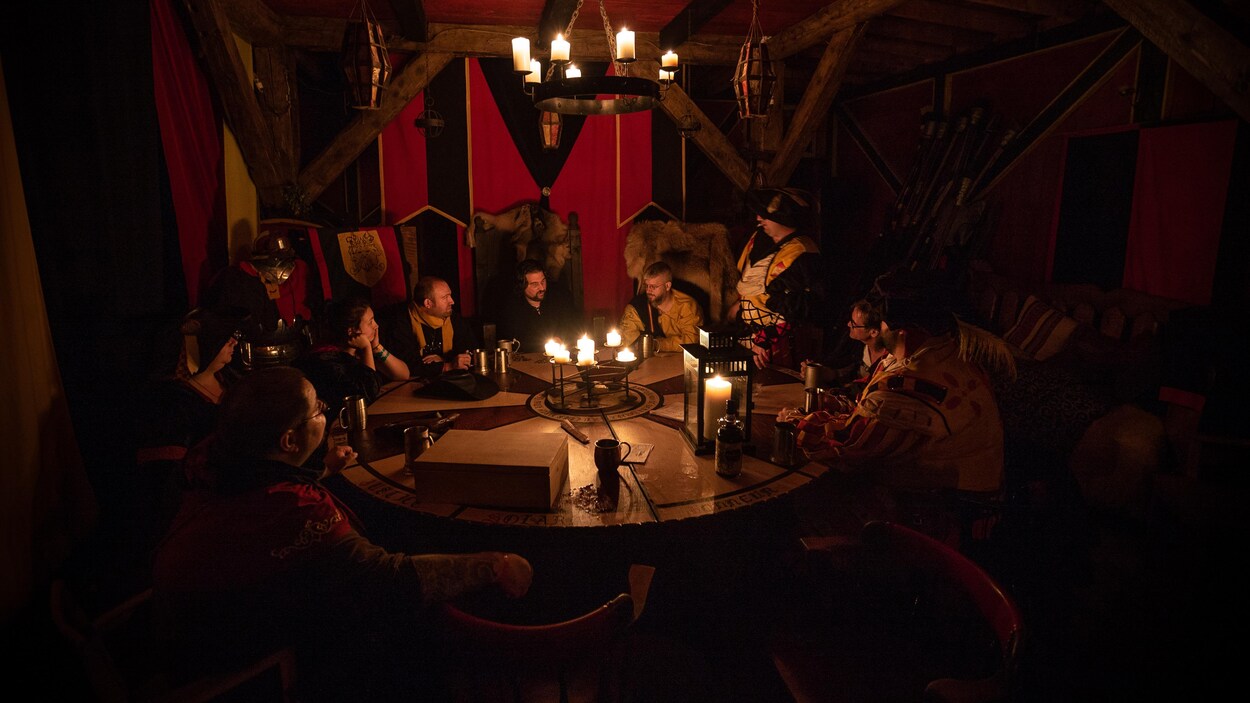 Des hommes autour d'une table dans une pièce éclairée aux chandelles.