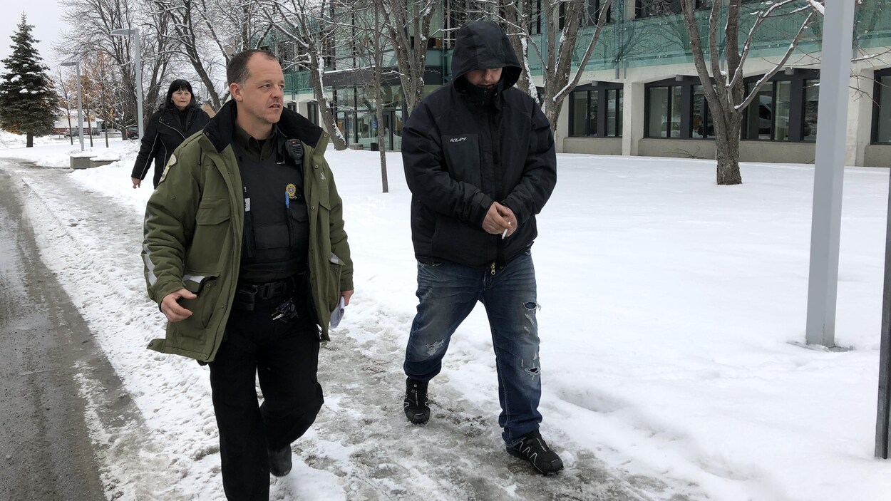 Un accusé est escorté par un policier au palais de justice de Val-d'Or.