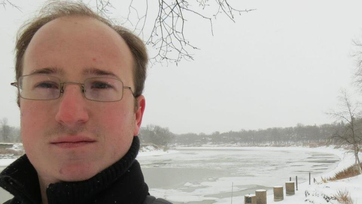 Un homme devant une rivière gelée.