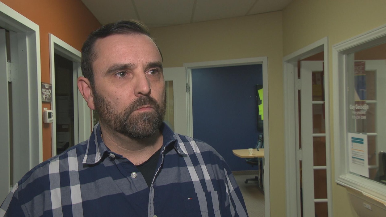L'homme est debout dans un corridor qui donne sur plusieurs pièces