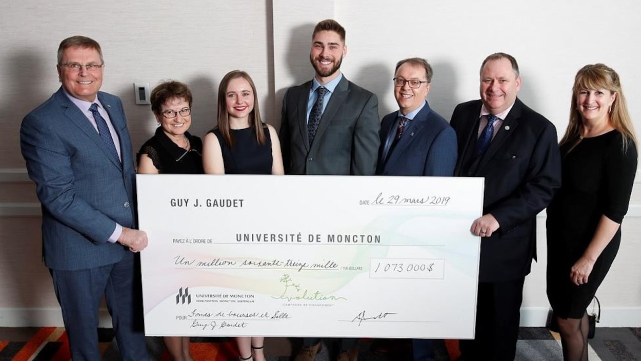Guy J. Gaudet, grand donateur à la campagne de financement de l'Université de Moncton, présente un chèque grand format à divers intervenants.