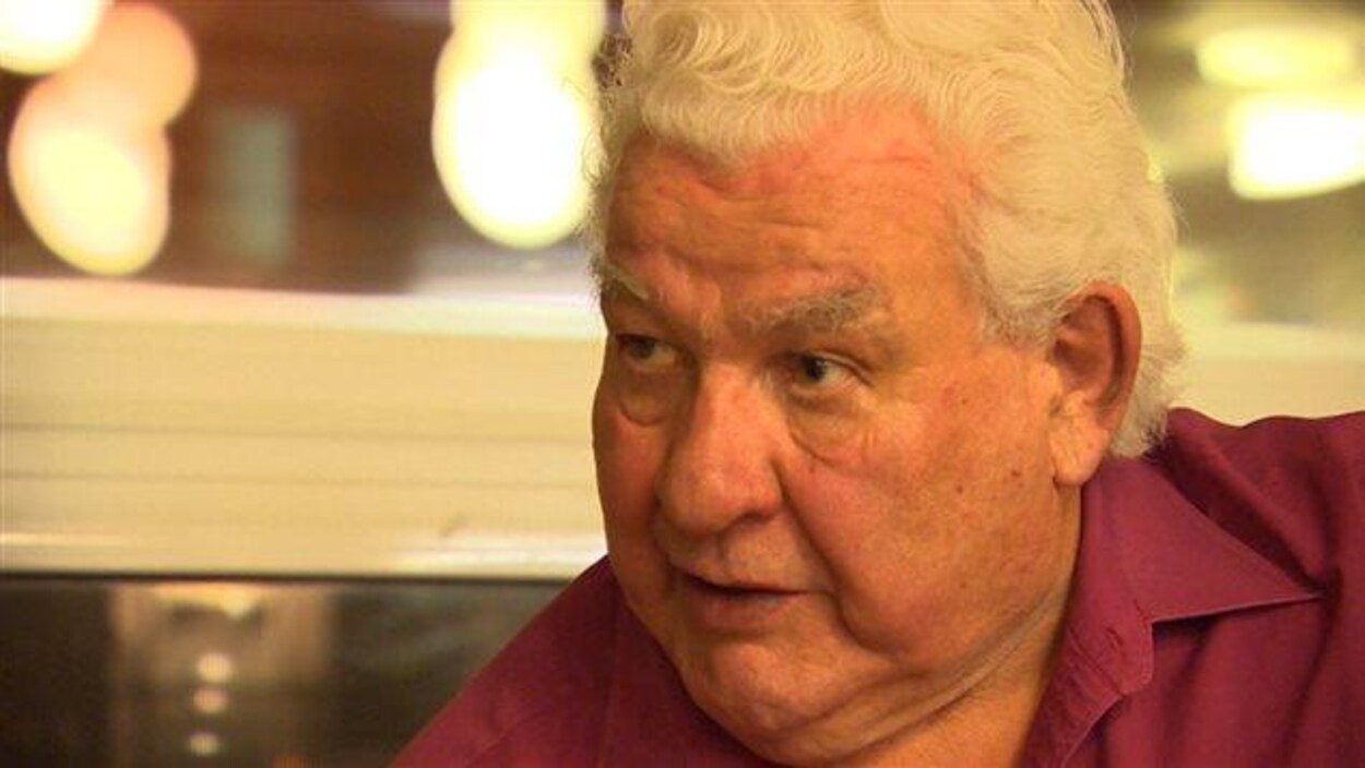 Un homme au cheveux blanc porte une chemise rouge. Un homme au cheveux blanc porte une chemise rouge.