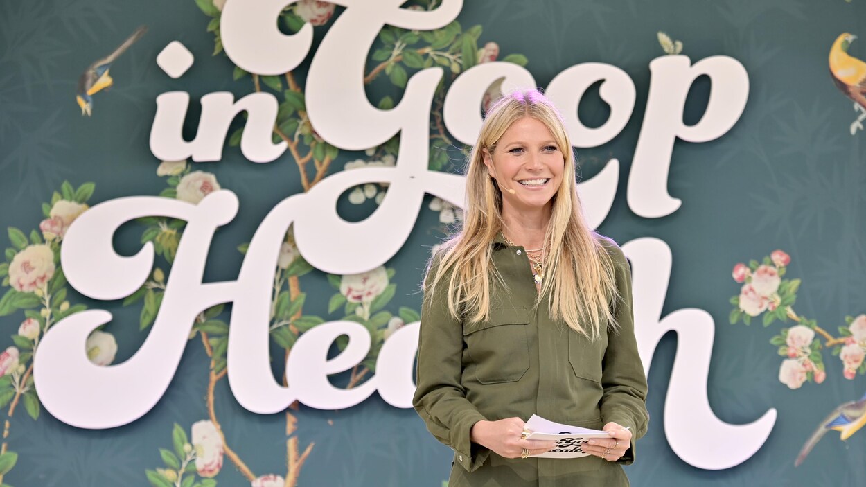 Gwyneth Platrow sur une scène. Elle tient des cartons dans ses mains. Derrière elle apparaît en grosses lettres le nom de l'événement.