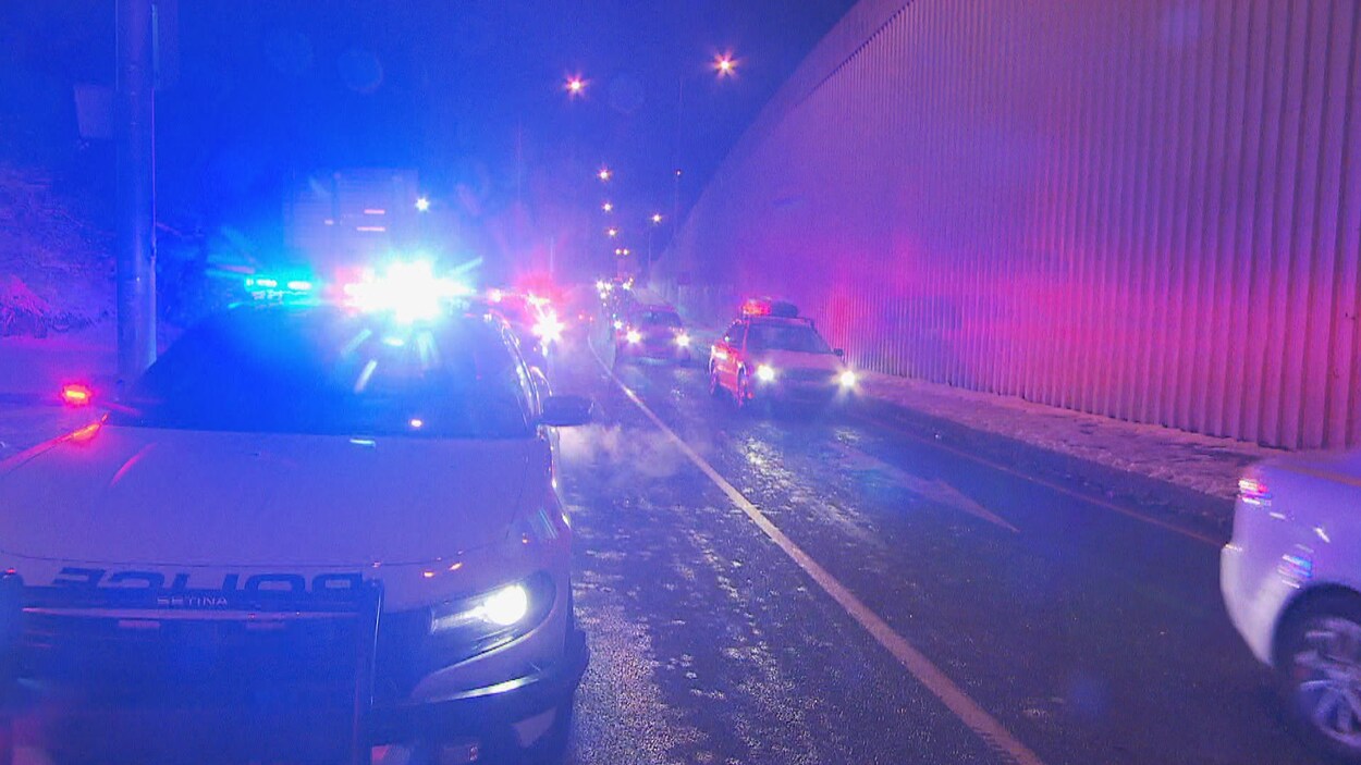 Une voiture de police en avant-plan. Des voitures circulent à droite.